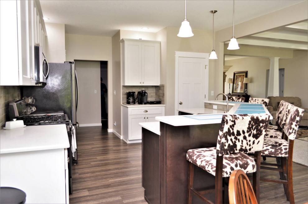 Open concept kitchen - mid-sized transitional single-wall open concept kitchen idea with a drop-in sink, shaker cabinets, white cabinets, quartzite countertops, beige backsplash, stainless steel appliances, an island and white countertops