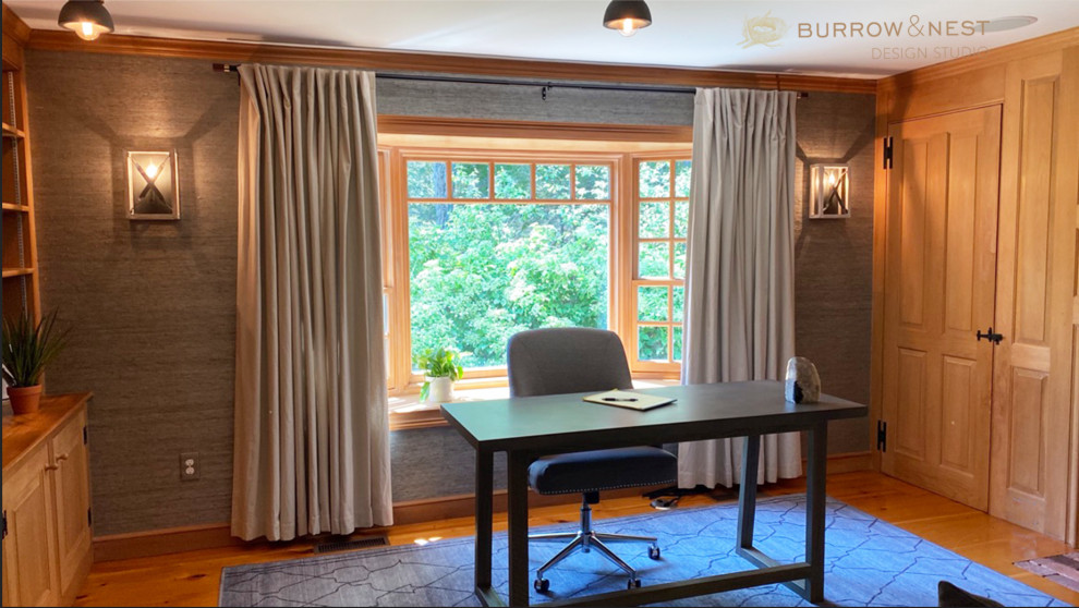 Large country home office in Providence with a library, grey walls, medium hardwood floors, a wood fireplace surround, a built-in desk, brown floor and wallpaper.