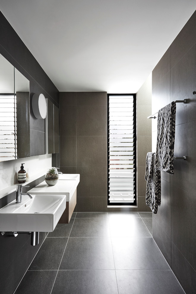 Inspiration for a mid-sized contemporary master bathroom in Melbourne with medium wood cabinets, an open shower, gray tile, ceramic tile, grey walls, porcelain floors, a wall-mount sink, solid surface benchtops and flat-panel cabinets.