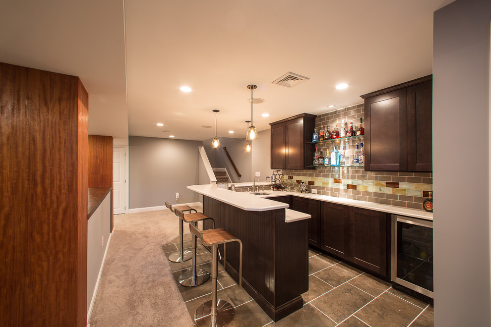 This is an example of a small modern u-shaped seated home bar in Philadelphia with an undermount sink, shaker cabinets, dark wood cabinets, laminate benchtops, brown splashback, ceramic splashback, slate floors and brown floor.