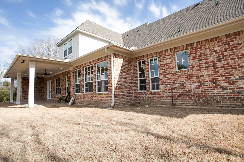 Photo of a large traditional two-storey brick red exterior in Dallas with a clipped gable roof.