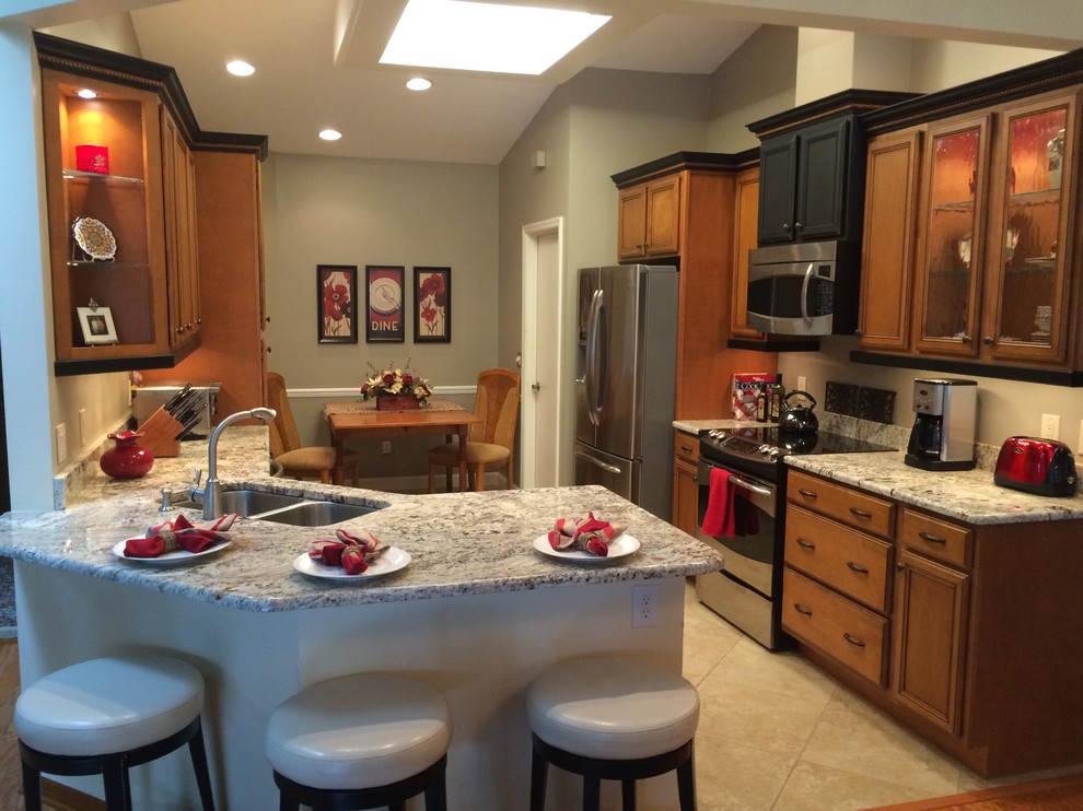 Eat-in kitchen - mid-sized transitional l-shaped porcelain tile eat-in kitchen idea in Orlando with an undermount sink, recessed-panel cabinets, medium tone wood cabinets, granite countertops, brown backsplash, stainless steel appliances and a peninsula