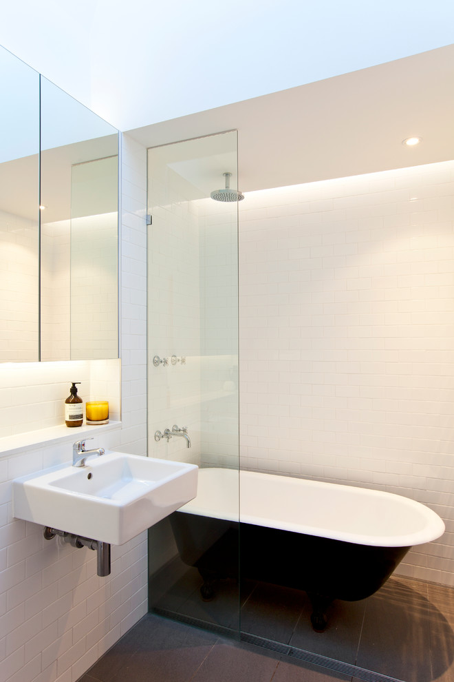 This is an example of a contemporary bathroom in Other with a claw-foot tub, subway tile and a wall-mount sink.