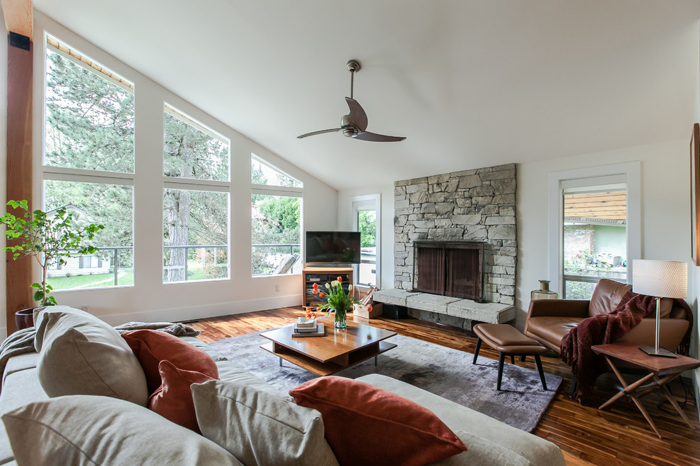 Photo of a mid-sized contemporary open concept living room in Vancouver with medium hardwood floors, a standard fireplace and a wood fireplace surround.