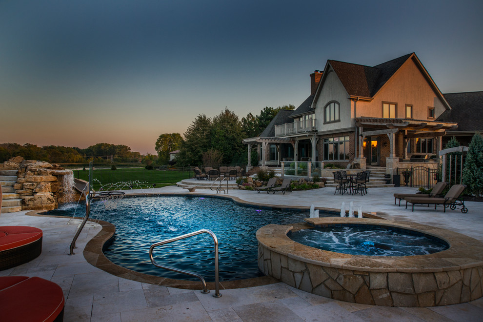 Inspiration for a mid-sized traditional backyard custom-shaped natural pool in Chicago with a hot tub and natural stone pavers.