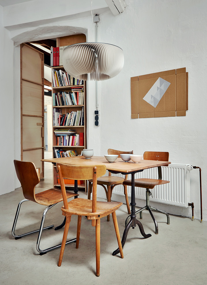 Photo of a mid-sized industrial dining room in Hamburg with white walls and concrete floors.
