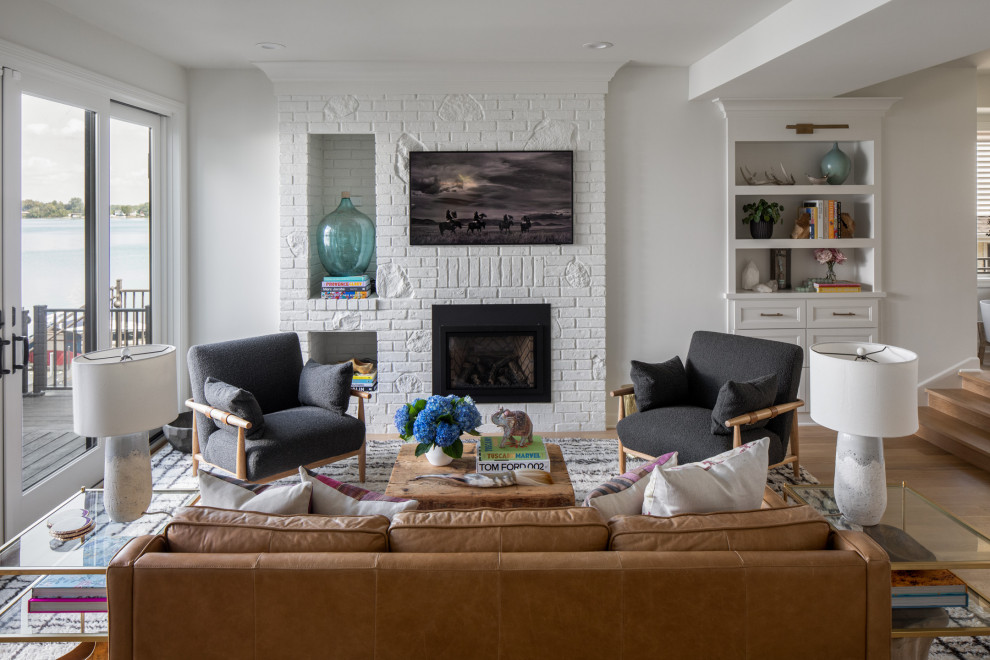 Design ideas for a mid-sized beach style open concept family room in Minneapolis with white walls, light hardwood floors, brown floor, a standard fireplace, a brick fireplace surround and a wall-mounted tv.