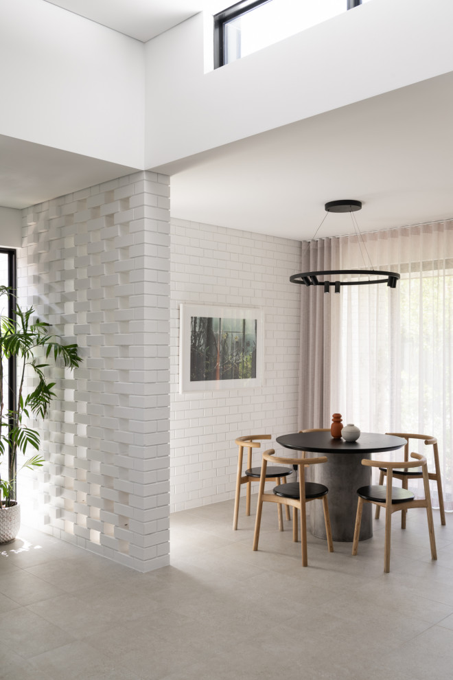 Réalisation d'une salle à manger design avec un mur blanc, un sol gris et un mur en parement de brique.