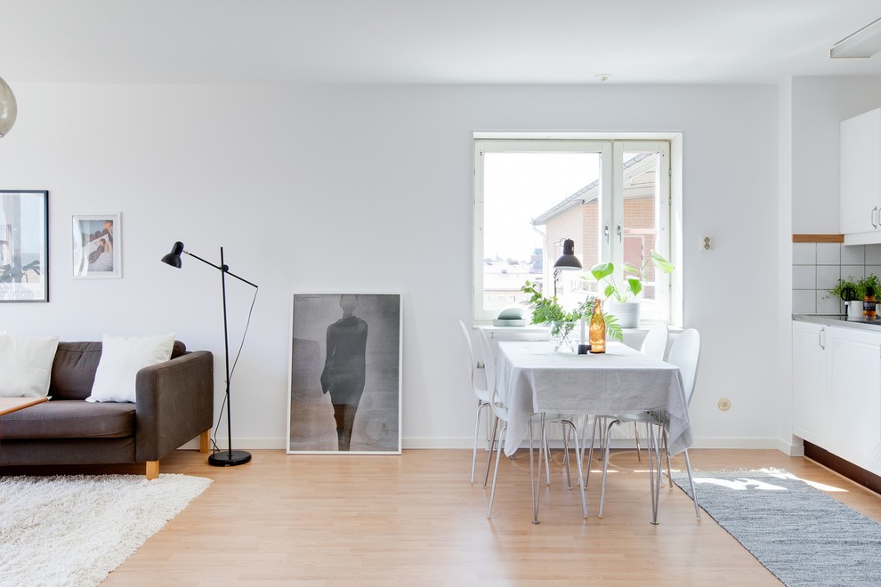 Photo of a scandinavian open plan dining in Stockholm with white walls, light hardwood floors and beige floor.