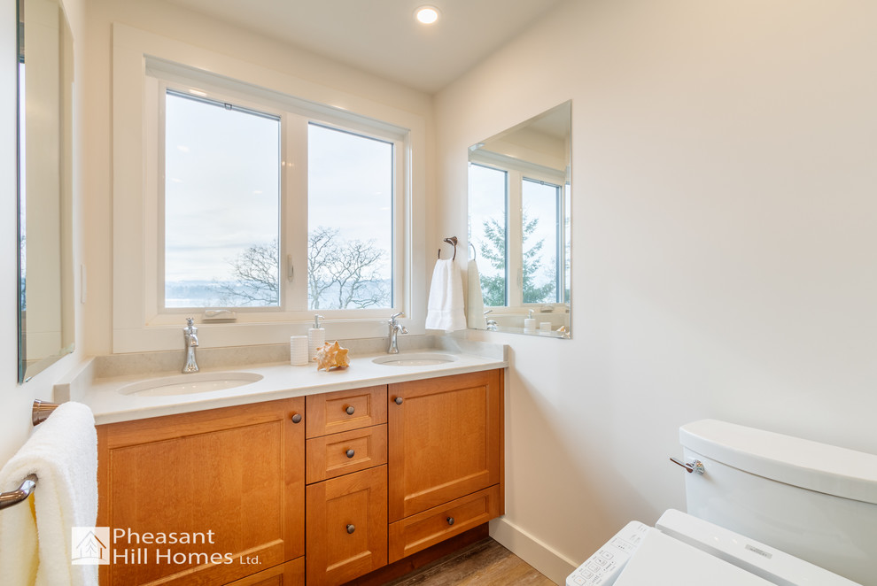 Inspiration for a mid-sized contemporary 3/4 laminate floor and beige floor corner shower remodel in Vancouver with shaker cabinets, medium tone wood cabinets, a bidet, beige walls, an undermount sink, quartz countertops, a hinged shower door and white countertops