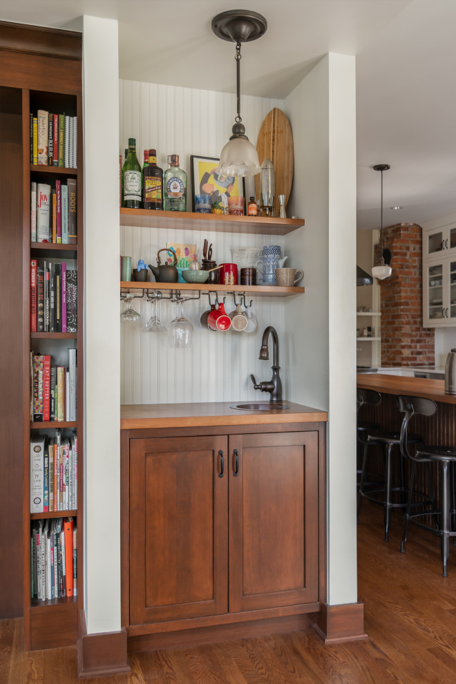 This is an example of a mid-sized arts and crafts home bar in Seattle with white cabinets, wood benchtops, shaker cabinets, timber splashback and medium hardwood floors.