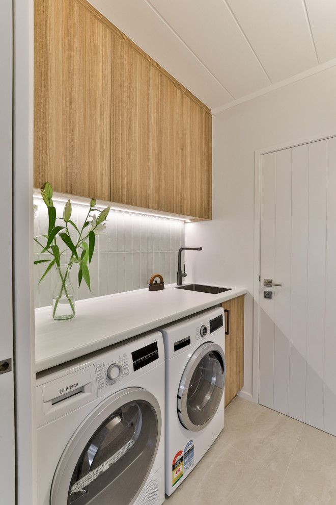 This is an example of a Small modern laundry room With an Undermount Sink, Light Wood Cabinets and a Side-by-side Washer and Dryer.