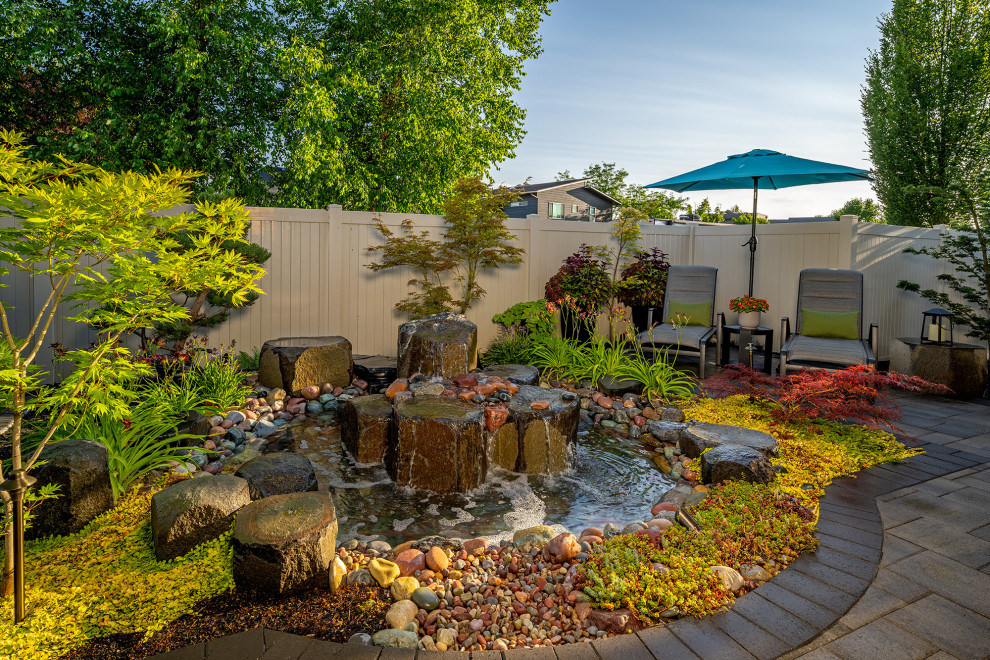 Small asian backyard formal garden in Seattle with a water feature, natural stone pavers and a wood fence.