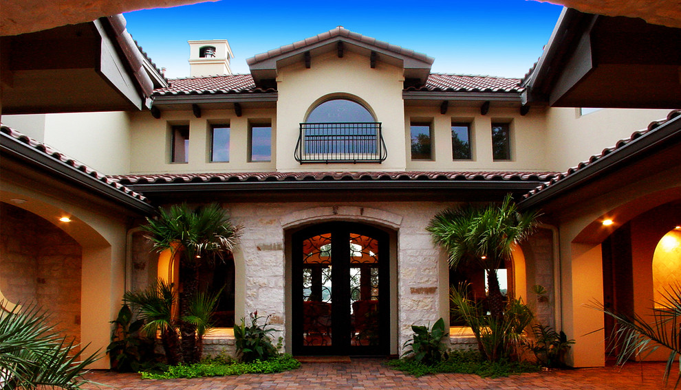 Large mediterranean two-storey stucco beige exterior in Austin with a hip roof.