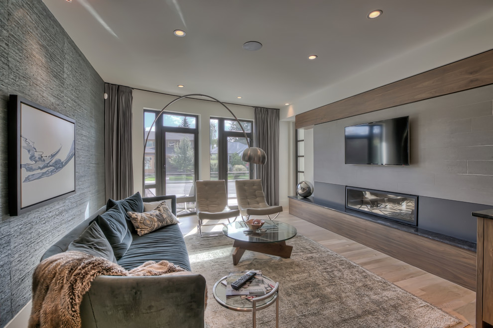 Photo of a mid-sized enclosed living room in Calgary with grey walls, light hardwood floors, a ribbon fireplace, a tile fireplace surround and a wall-mounted tv.