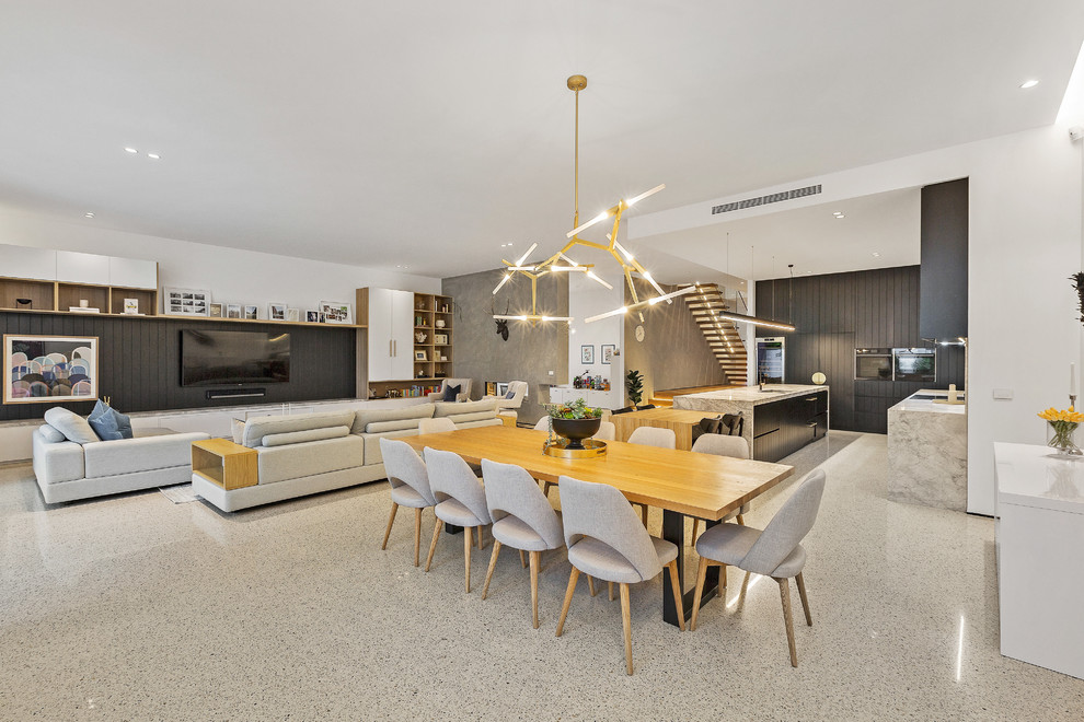 Large modern open plan dining in Melbourne with white walls, concrete floors and white floor.