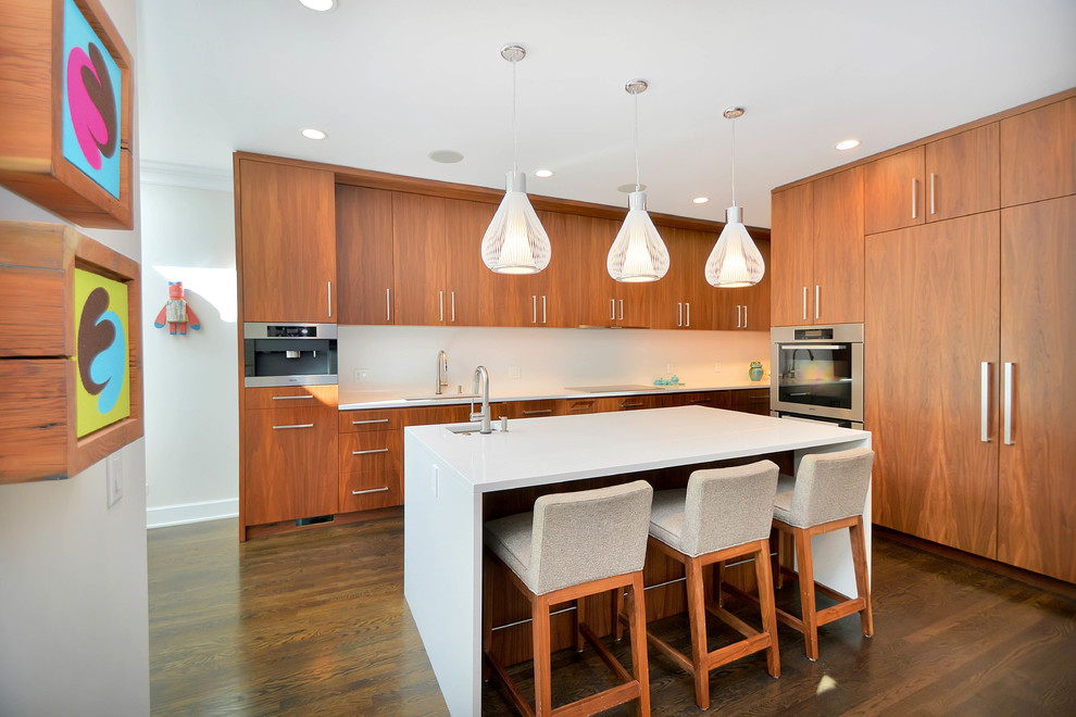 This is an example of a large contemporary open plan kitchen in Chicago with an undermount sink, flat-panel cabinets, medium wood cabinets, quartz benchtops, white splashback, stone slab splashback, panelled appliances, dark hardwood floors and with island.