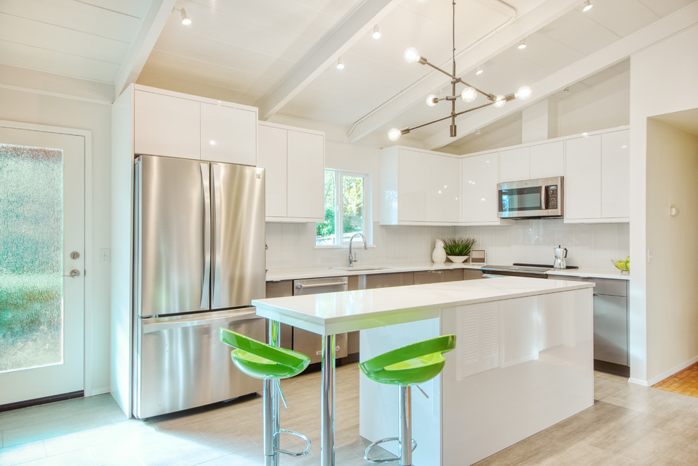 Inspiration for a mid-sized modern l-shaped open plan kitchen in Seattle with an undermount sink, flat-panel cabinets, white cabinets, quartz benchtops, white splashback, glass sheet splashback, stainless steel appliances, ceramic floors, with island, grey floor, white benchtop and timber.