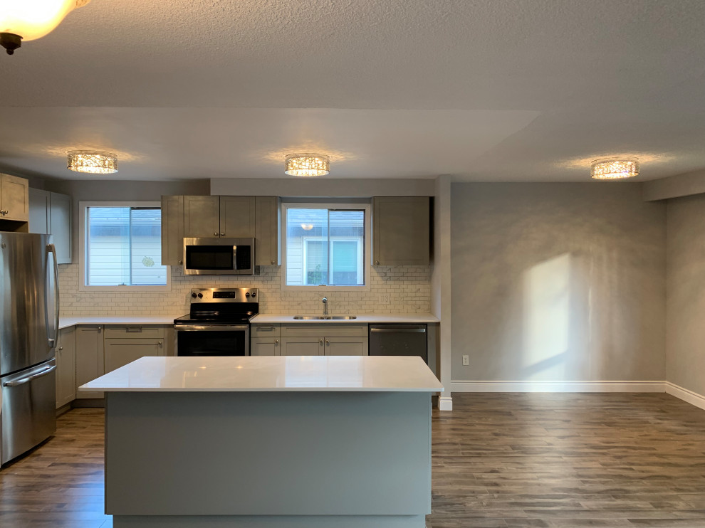 Kitchen - large transitional l-shaped medium tone wood floor kitchen idea with an undermount sink, shaker cabinets, gray cabinets, quartz countertops, white backsplash, marble backsplash, stainless steel appliances, an island and white countertops