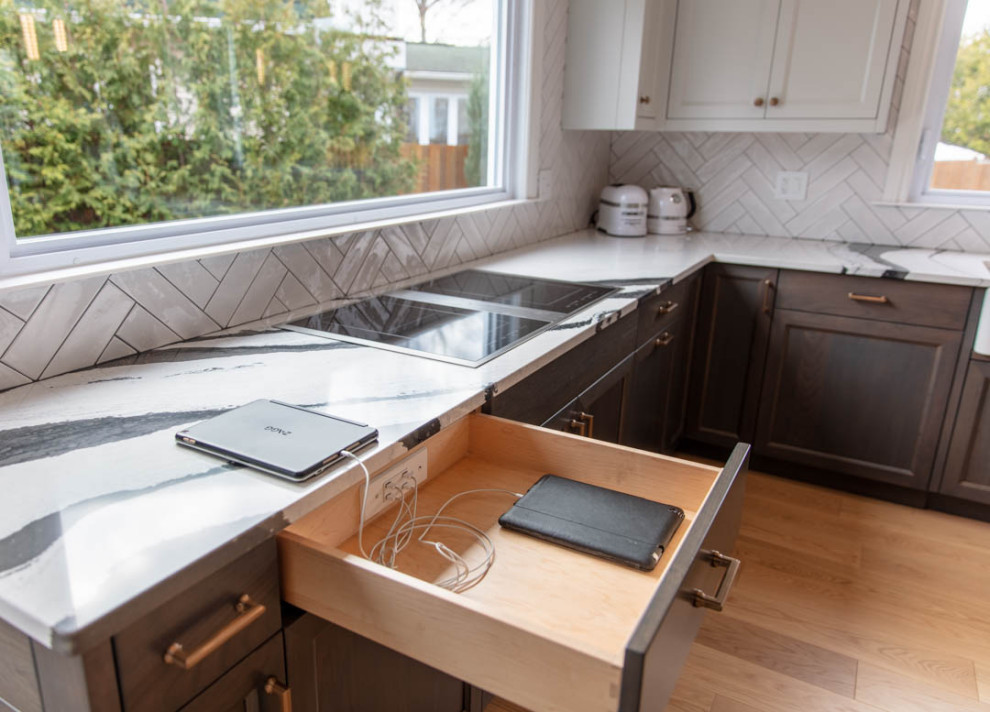 Open concept kitchen - transitional u-shaped light wood floor open concept kitchen idea in Ottawa with a farmhouse sink, recessed-panel cabinets, dark wood cabinets, quartz countertops, white backsplash, porcelain backsplash, paneled appliances, a peninsula and black countertops