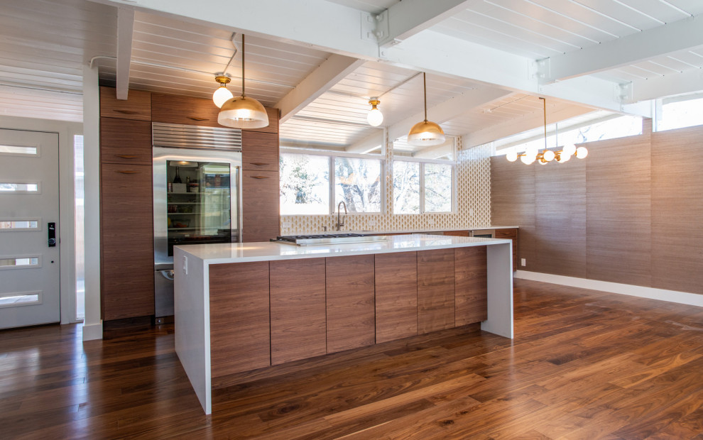 Design ideas for a medium sized contemporary l-shaped open plan kitchen in Santa Barbara with a submerged sink, flat-panel cabinets, medium wood cabinets, engineered stone countertops, stainless steel appliances, medium hardwood flooring, an island and white worktops.