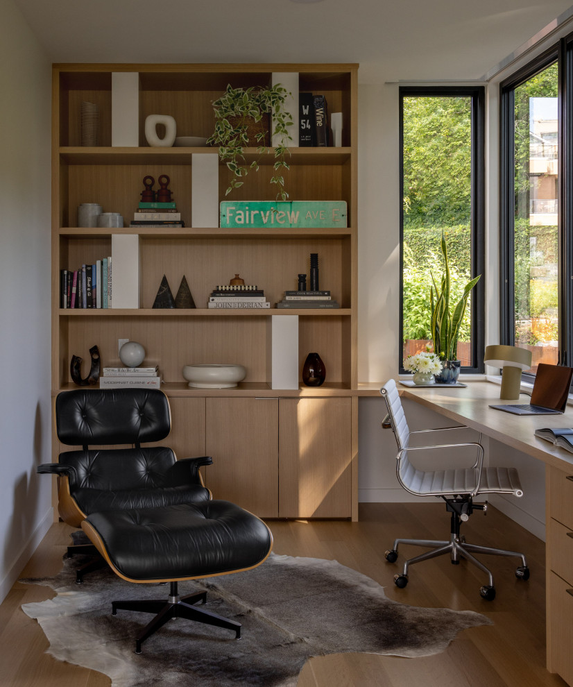 Example of a trendy built-in desk medium tone wood floor study room design in Seattle with white walls