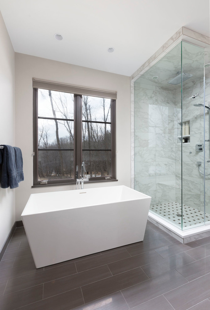 Photo of a large contemporary master bathroom in Milwaukee with flat-panel cabinets, dark wood cabinets, a freestanding tub, a corner shower, gray tile, ceramic tile, grey walls, ceramic floors, grey floor and a hinged shower door.