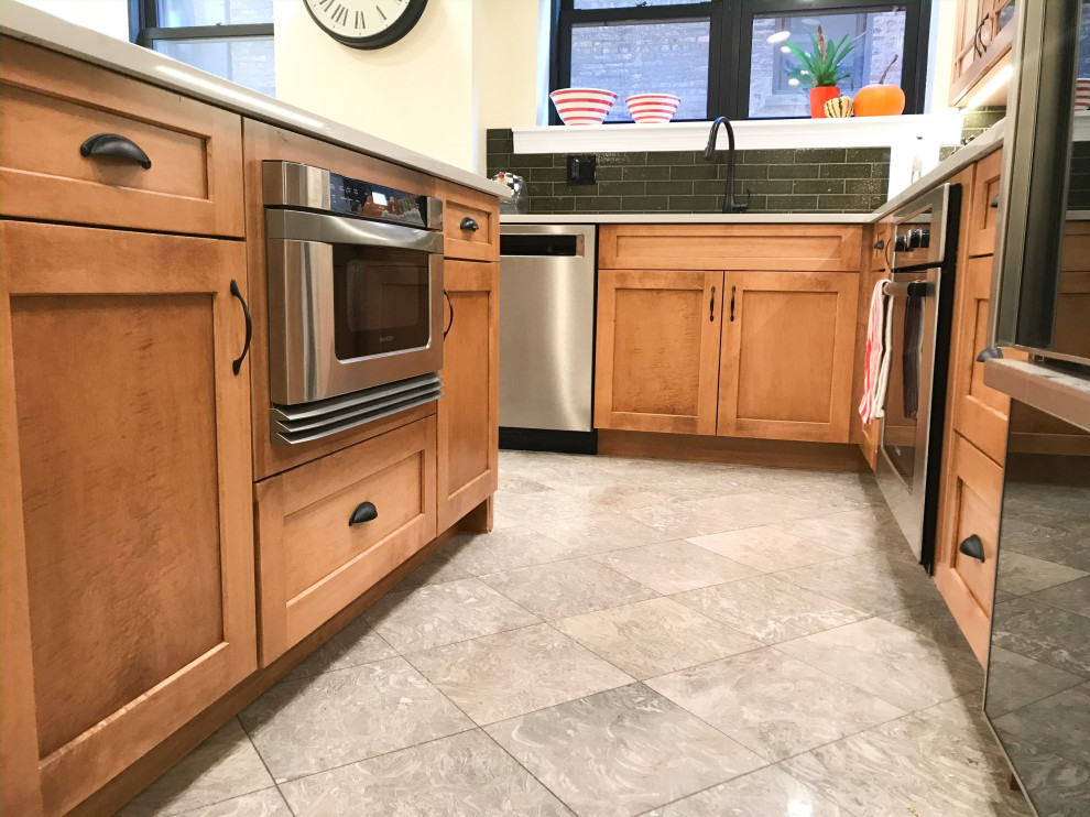 Mid-sized transitional l-shaped eat-in kitchen photo in Chicago with an undermount sink, shaker cabinets, brown cabinets, green backsplash, stainless steel appliances, an island and gray countertops