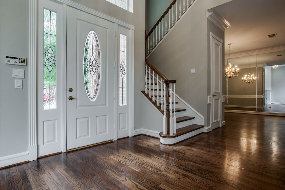 This is an example of a large traditional front door in Dallas with grey walls, dark hardwood floors, a single front door, a white front door and brown floor.