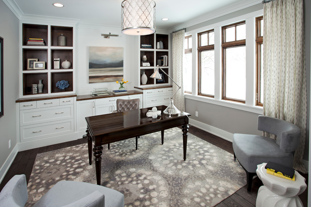 Photo of a large transitional home office in Minneapolis with grey walls, dark hardwood floors and a freestanding desk.