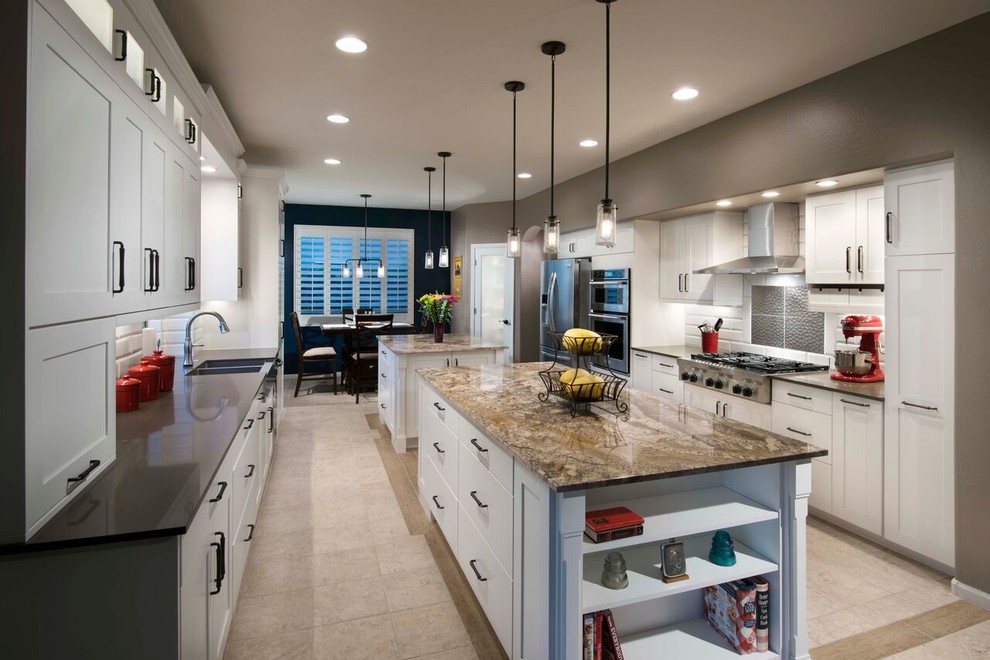 Example of a transitional u-shaped ceramic tile eat-in kitchen design in Phoenix with a farmhouse sink, shaker cabinets, white cabinets, granite countertops, white backsplash, ceramic backsplash, stainless steel appliances and two islands