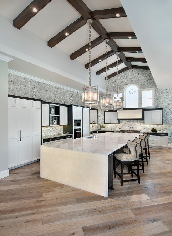 This is an example of an expansive transitional l-shaped eat-in kitchen in Miami with mosaic tile splashback, panelled appliances, light hardwood floors, with island, an undermount sink, shaker cabinets, multi-coloured splashback and onyx benchtops.