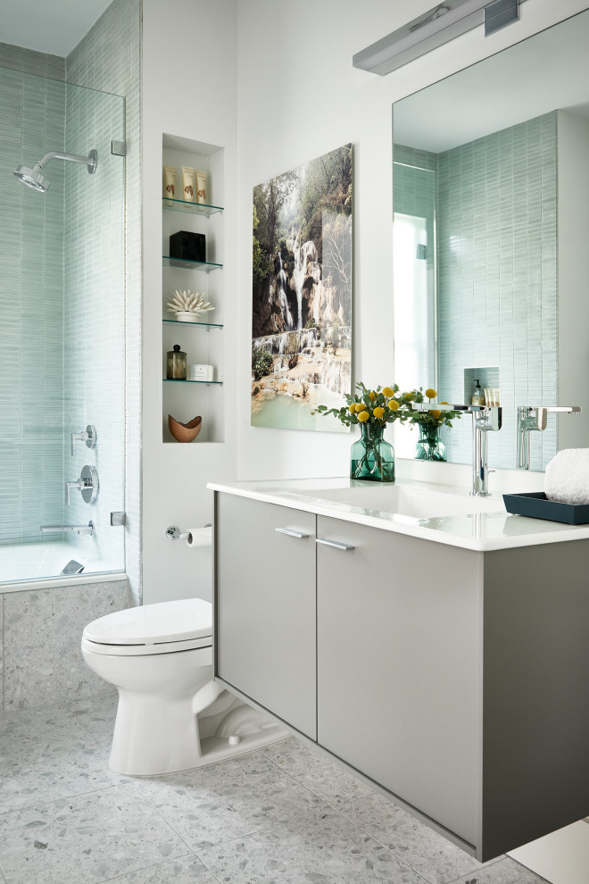 На фото: маленькая ванная комната в современном стиле с плоскими фасадами, серыми фасадами, полновстраиваемой ванной, открытым душем, унитазом-моноблоком, серой плиткой, керамической плиткой, белыми стенами, полом из терраццо, монолитной раковиной, столешницей из искусственного камня, серым полом, открытым душем, белой столешницей, тумбой под одну раковину и подвесной тумбой для на участке и в саду с