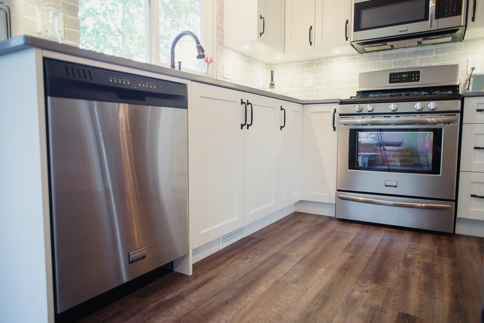 Eat-in kitchen - mid-sized transitional l-shaped brown floor eat-in kitchen idea in Vancouver with shaker cabinets, white cabinets, quartz countertops, gray backsplash, stainless steel appliances and an island