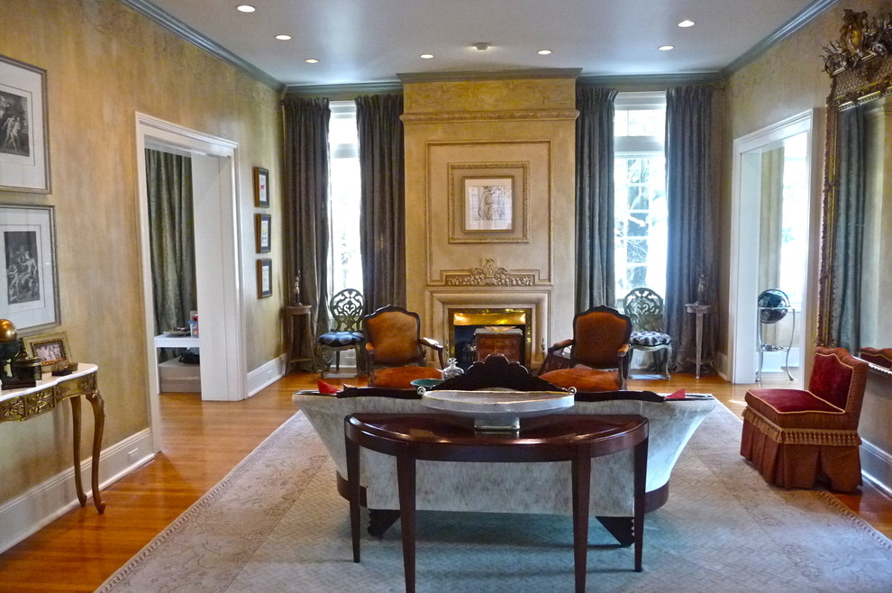 This is an example of a large traditional formal enclosed living room in New Orleans with beige walls, light hardwood floors, a standard fireplace and a plaster fireplace surround.