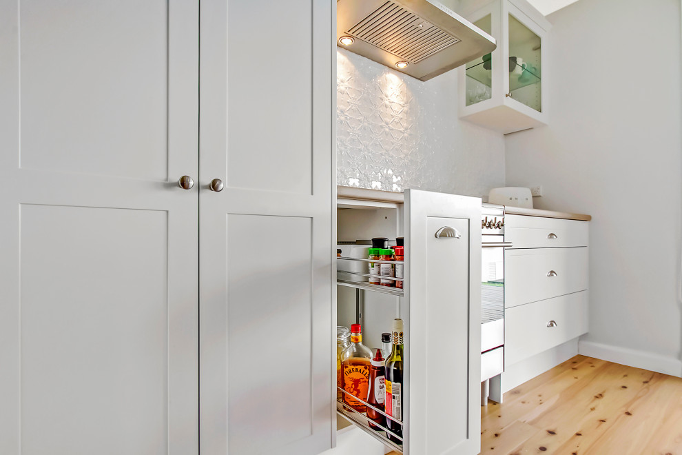 Photo of a mid-sized country eat-in kitchen in Sydney with an undermount sink, shaker cabinets, blue cabinets, quartz benchtops, metallic splashback, metal splashback, white appliances and with island.