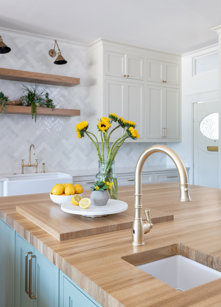 Inspiration for a mid-sized country u-shaped separate kitchen in Dallas with a farmhouse sink, shaker cabinets, white cabinets, quartz benchtops, white splashback, ceramic splashback, stainless steel appliances, light hardwood floors, multiple islands, brown floor and white benchtop.