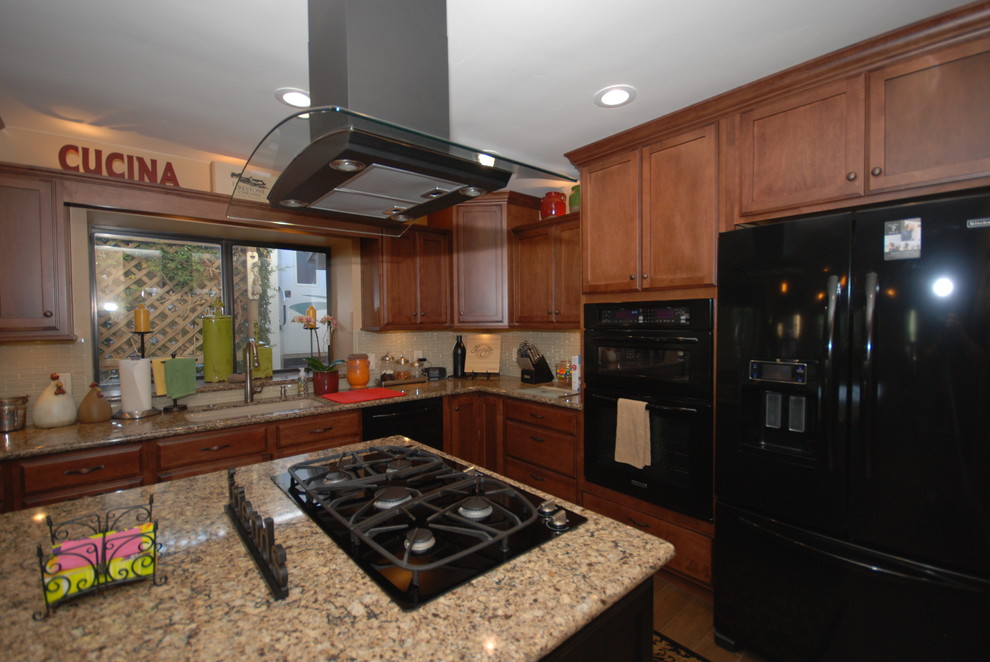 Example of a classic u-shaped eat-in kitchen design with an undermount sink, shaker cabinets, brown cabinets, quartz countertops, beige backsplash, glass sheet backsplash and black appliances
