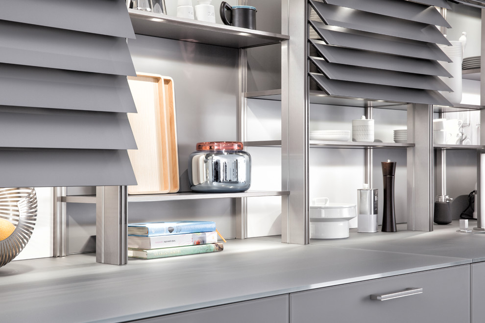 Inspiration for a large u-shaped dark wood floor eat-in kitchen remodel in Orange County with an undermount sink, glass-front cabinets, gray cabinets, glass countertops, gray backsplash, stainless steel appliances and an island