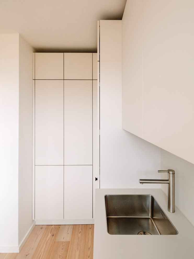 Esempio di una piccola cucina a L design chiusa con lavello da incasso, ante lisce, ante grigie, elettrodomestici neri e pavimento in legno verniciato