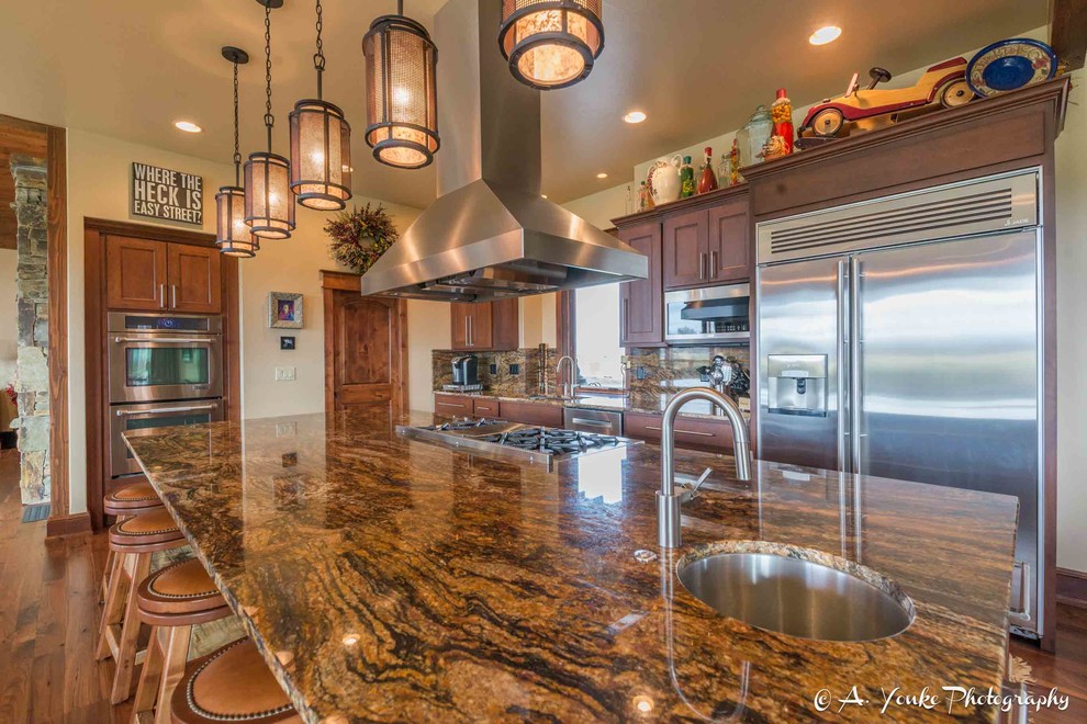 Example of a mid-sized mountain style l-shaped dark wood floor open concept kitchen design with an undermount sink, shaker cabinets, dark wood cabinets, granite countertops, multicolored backsplash, stone slab backsplash, stainless steel appliances and an island