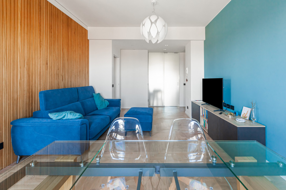 На фото: открытая гостиная комната среднего размера в стиле ретро с синими стенами, деревянным полом, мультимедийным центром и стенами из вагонки с