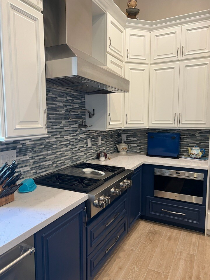 Expansive midcentury l-shaped eat-in kitchen in Phoenix with a farmhouse sink, raised-panel cabinets, blue cabinets, quartzite benchtops, multi-coloured splashback, glass tile splashback, stainless steel appliances, with island and white benchtop.