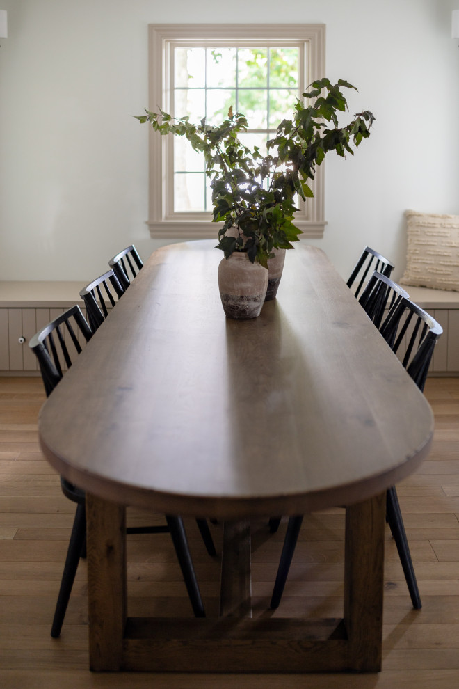 Immagine di una sala da pranzo aperta verso la cucina con pareti bianche, pavimento in legno massello medio e pavimento marrone