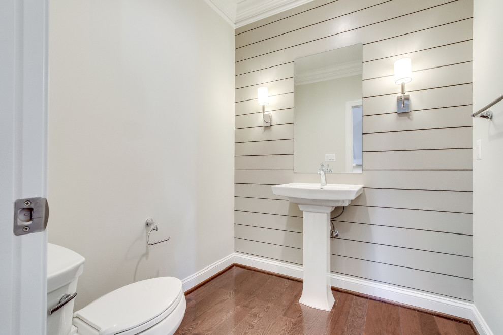 Design ideas for a mid-sized arts and crafts bathroom in DC Metro with white cabinets, a two-piece toilet, white tile, grey walls, dark hardwood floors, a pedestal sink, brown floor, white benchtops, a single vanity, a freestanding vanity and planked wall panelling.