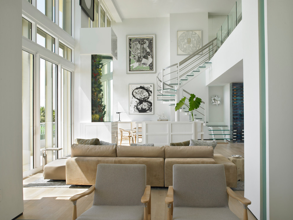 This is an example of an expansive contemporary open concept family room in Miami with white walls, light hardwood floors and black floor.