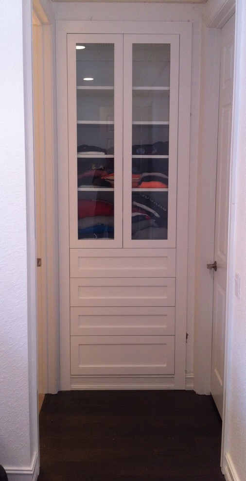 Photo of a small transitional gender-neutral dressing room in Miami with shaker cabinets, white cabinets and dark hardwood floors.