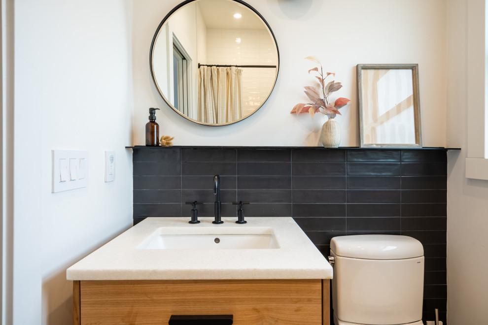 Photo of a small traditional bathroom in San Francisco with flat-panel cabinets, light wood cabinets, an alcove bath, a shower/bath combination, a two-piece toilet, black and white tiles, porcelain tiles, white walls, ceramic flooring, a submerged sink, engineered stone worktops, beige floors, a shower curtain, white worktops, a wall niche, a single sink and a floating vanity unit.