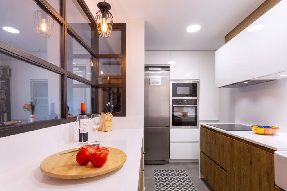 Inspiration for a contemporary galley separate kitchen in Barcelona with a single-bowl sink, medium wood cabinets, white splashback, stainless steel appliances, no island, white benchtop and recessed.