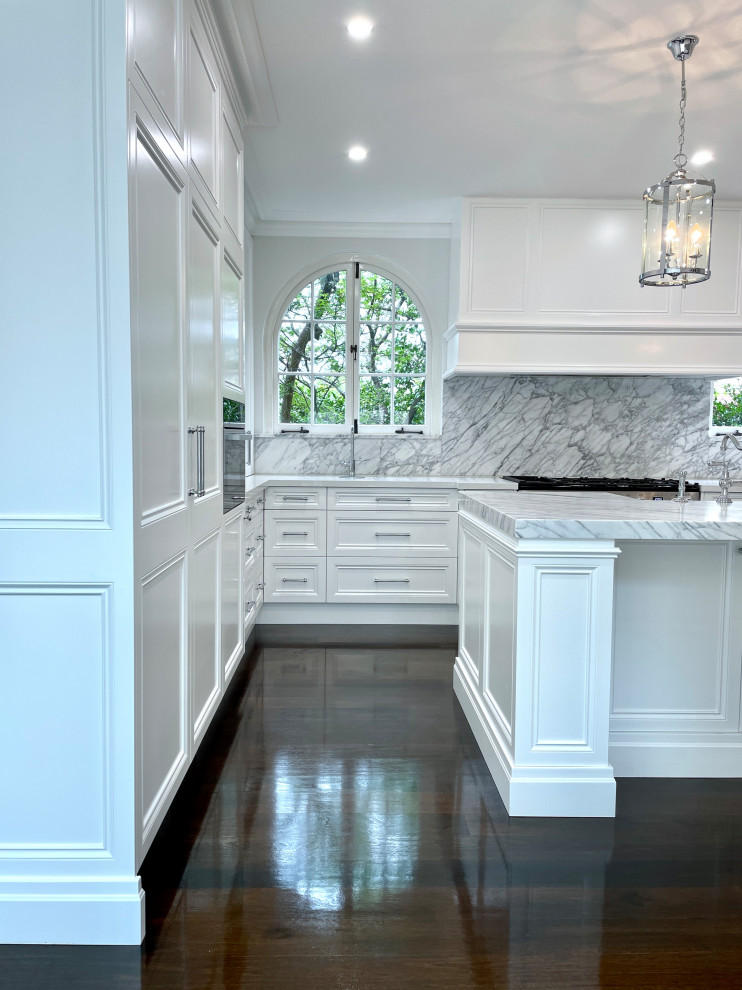 This is an example of an expansive traditional u-shaped kitchen pantry in Sydney with a farmhouse sink, recessed-panel cabinets, white cabinets, marble benchtops, grey splashback, marble splashback, stainless steel appliances, dark hardwood floors, with island, brown floor, grey benchtop and recessed.